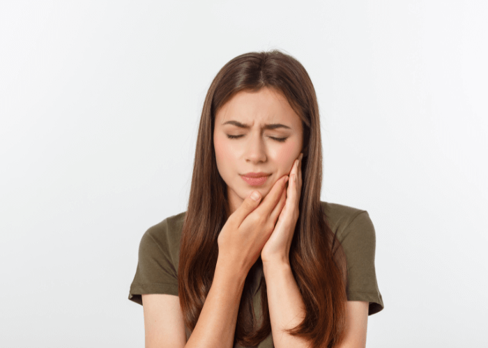 woman holding her jaw in discomfort
