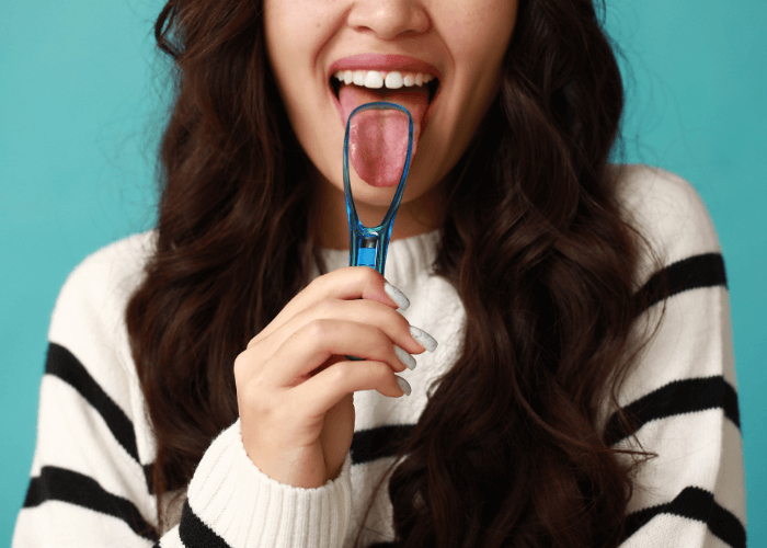 woman scrapping her tongue with a tongue scrapper