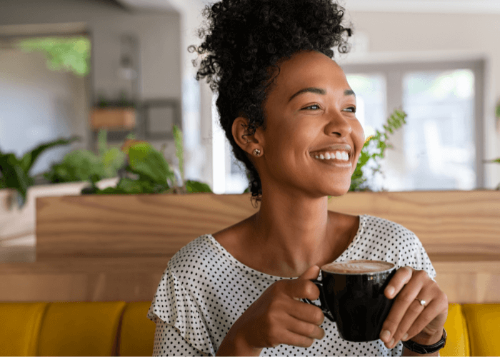 woman smiling while holding coffee in her living room