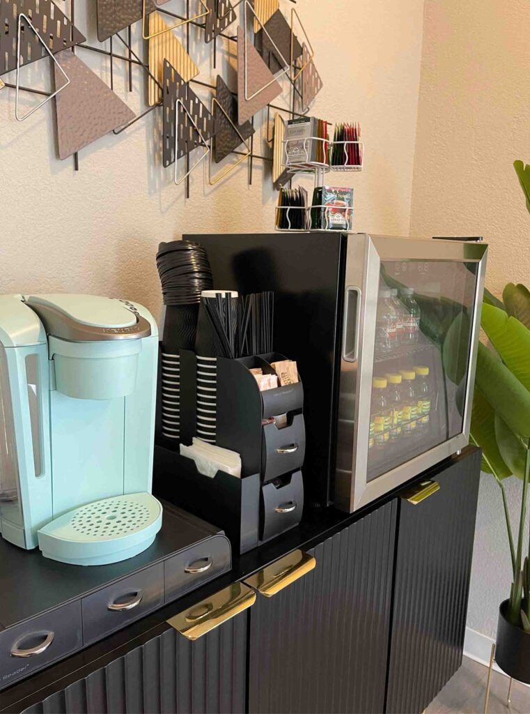 beverage station with a coffee maker, fridge, and utensils